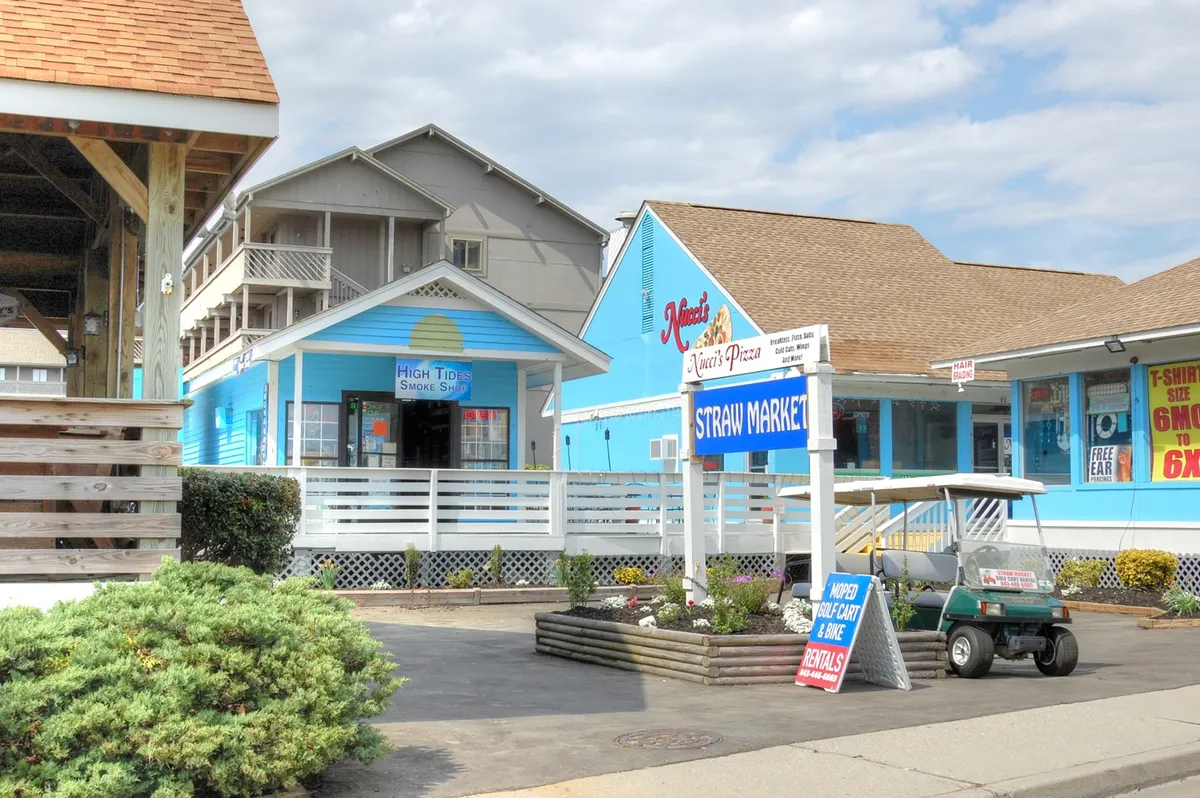 A vibrant streetscape with colorful buildings, signage, a golf cart, and well-kept landscaping. The area bustles with opportunities for shopping, dining, and leisure walks, conveying the variety of experiences available in the neighborhood.