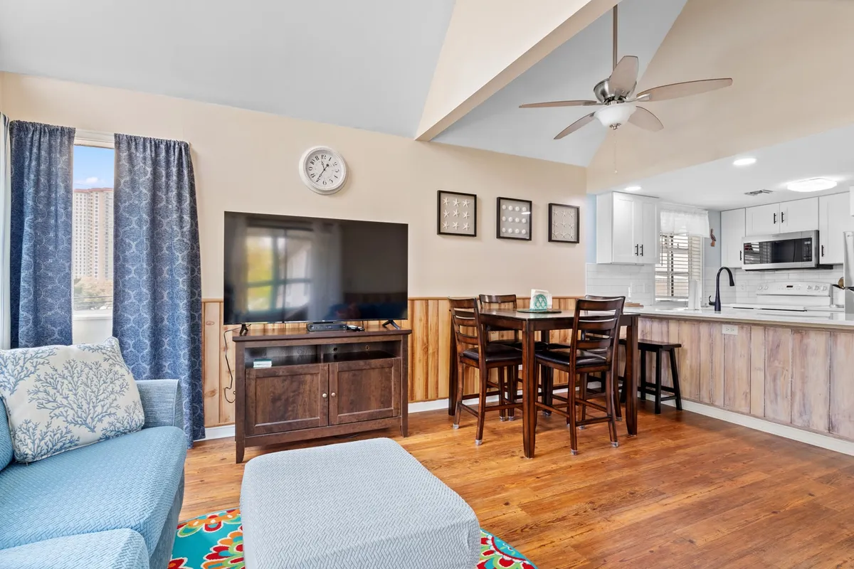 This image showcases a blue couch, a dining table, and a television, creating a multifunctional space for family gatherings, movie nights, or meals together. The setup is informal yet inviting, ideal for shared experiences.