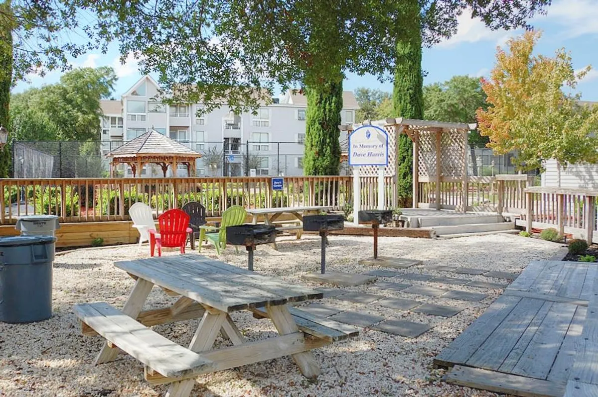 A communal outdoor grilling and picnic area featuring grill stations, colorful chairs, shaded gazebo, and picnic tables. The scene encourages social gatherings, alfresco dining, and relaxed group activities.
