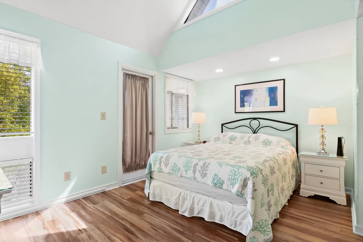 This image features a bed with patterned bedding, a nightstand with a lamp, and calming artwork on the wall. The room feels tranquil and well-appointed, with soft lighting perfect for relaxation after a busy day.