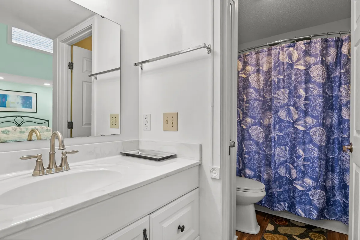 A tasteful bathroom scene with a vanity sink, mirror, and shower curtain. The space feels clean, modern, and serene—ideal for personal grooming and relaxation after a fun-filled day.